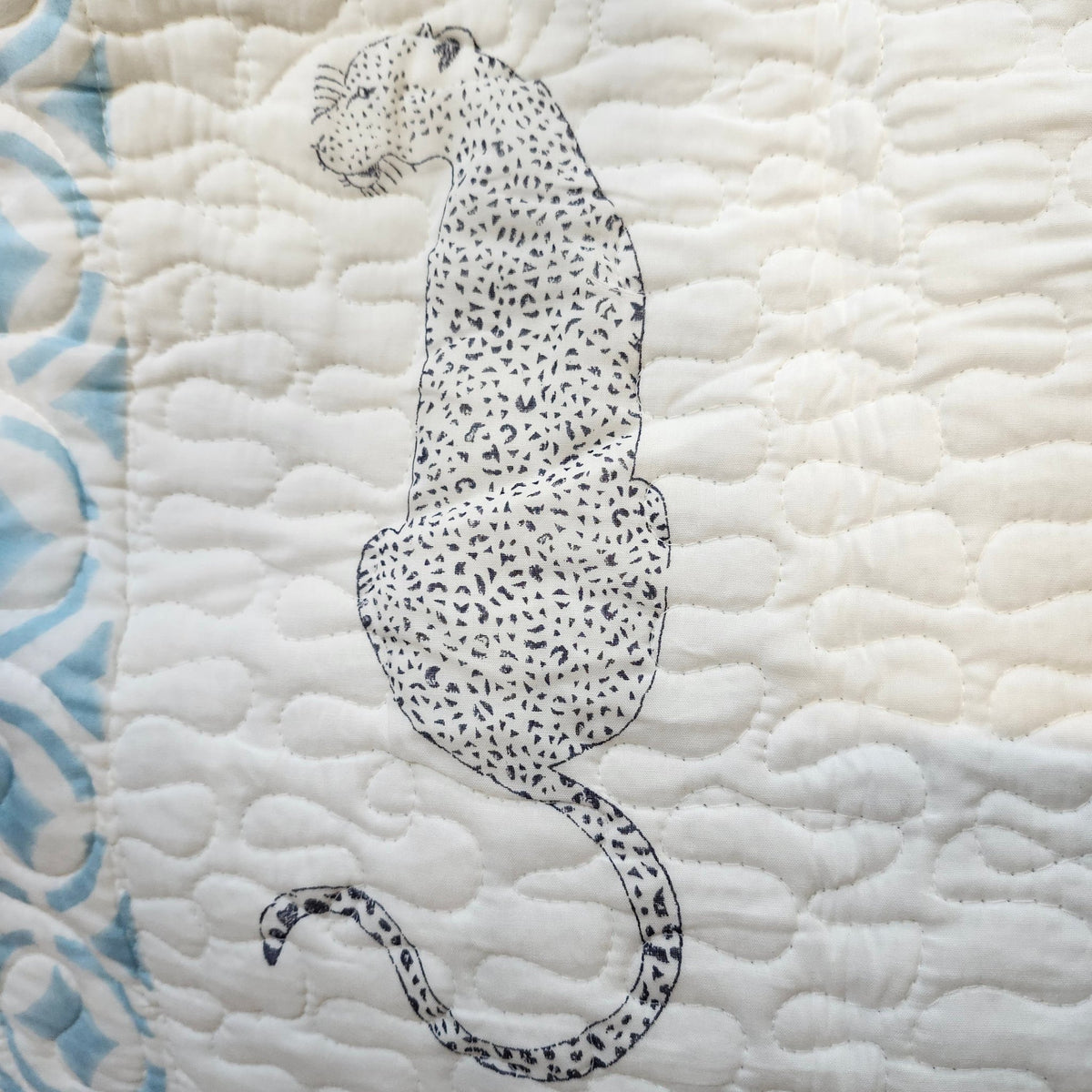 Detail of the blue cheetah and palm tree block print on the reversible bedspread, each piece slightly different.