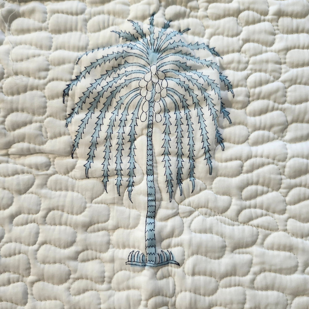 Reverse of the Cheetah bedspread, a blue geometric block print on white cotton, lightly quilted and made in India.