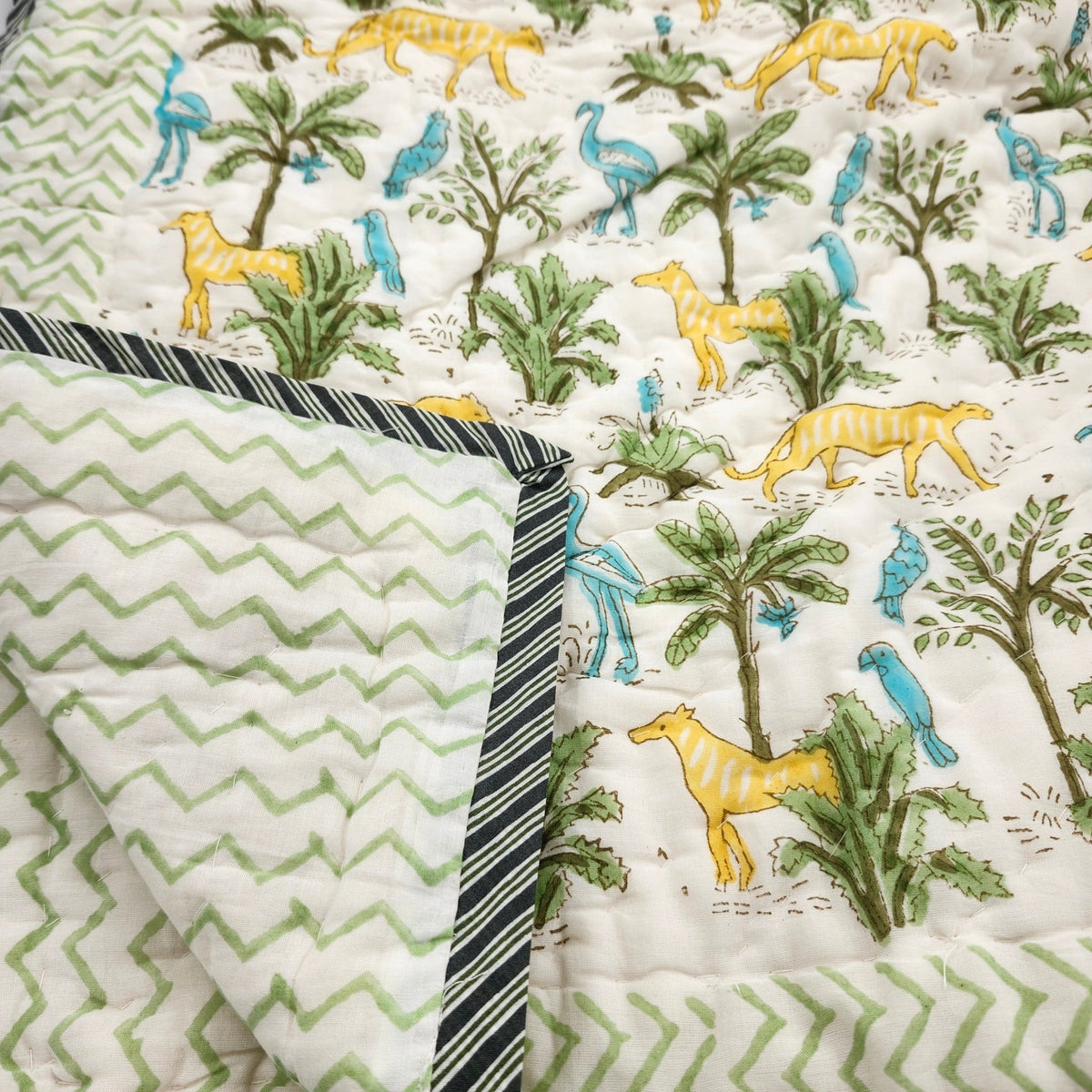 Child's block print quilt with a jungle print of yellow big cats and blue birds, in organic cotton cambric
