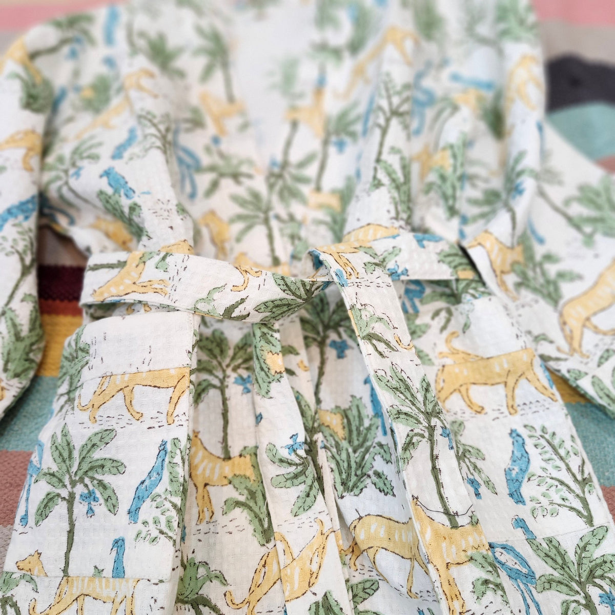 Child's cotton waffle bath robe in a jungle print of large cats, birds and trees, with matching belt and pockets