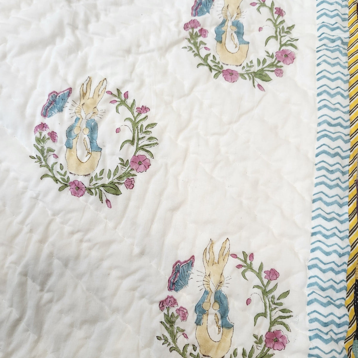 Soft organic cotton cambric quilt for a child, printed with Peter Rabbit on one side and blue spots on the other