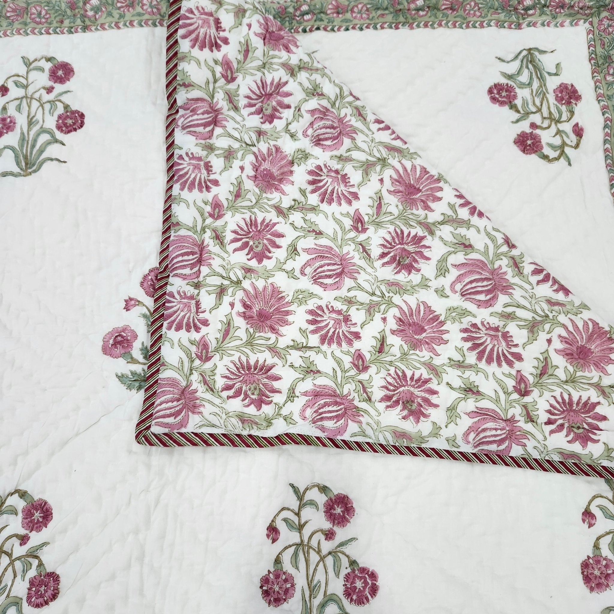 Reversible single cotton quilt with a pink carnation block print on one side and a contrasting floral print on the other.