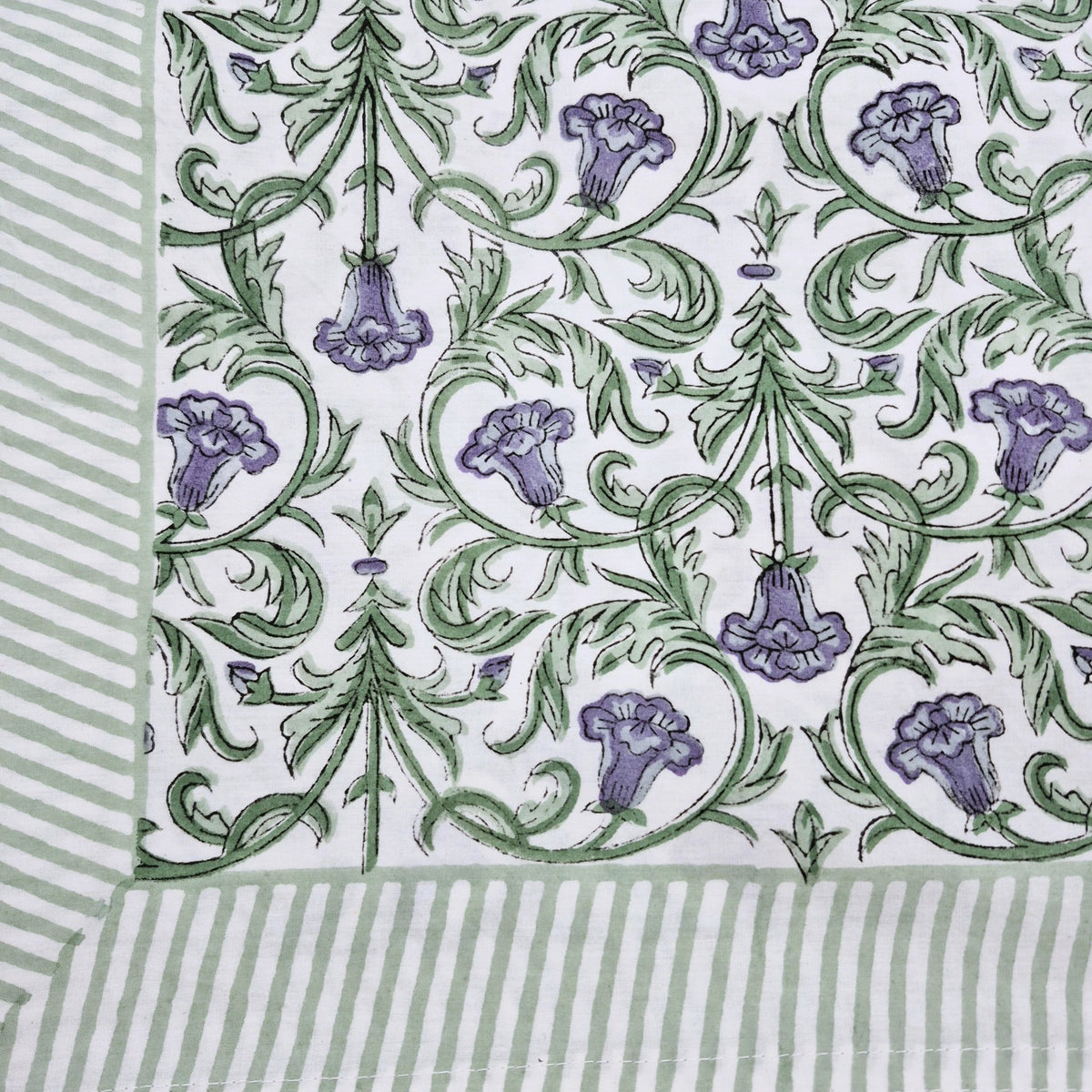 Cotton block print tablecloth with violet flowers and green foliage on white, 150 x 225cm, with a striped border.