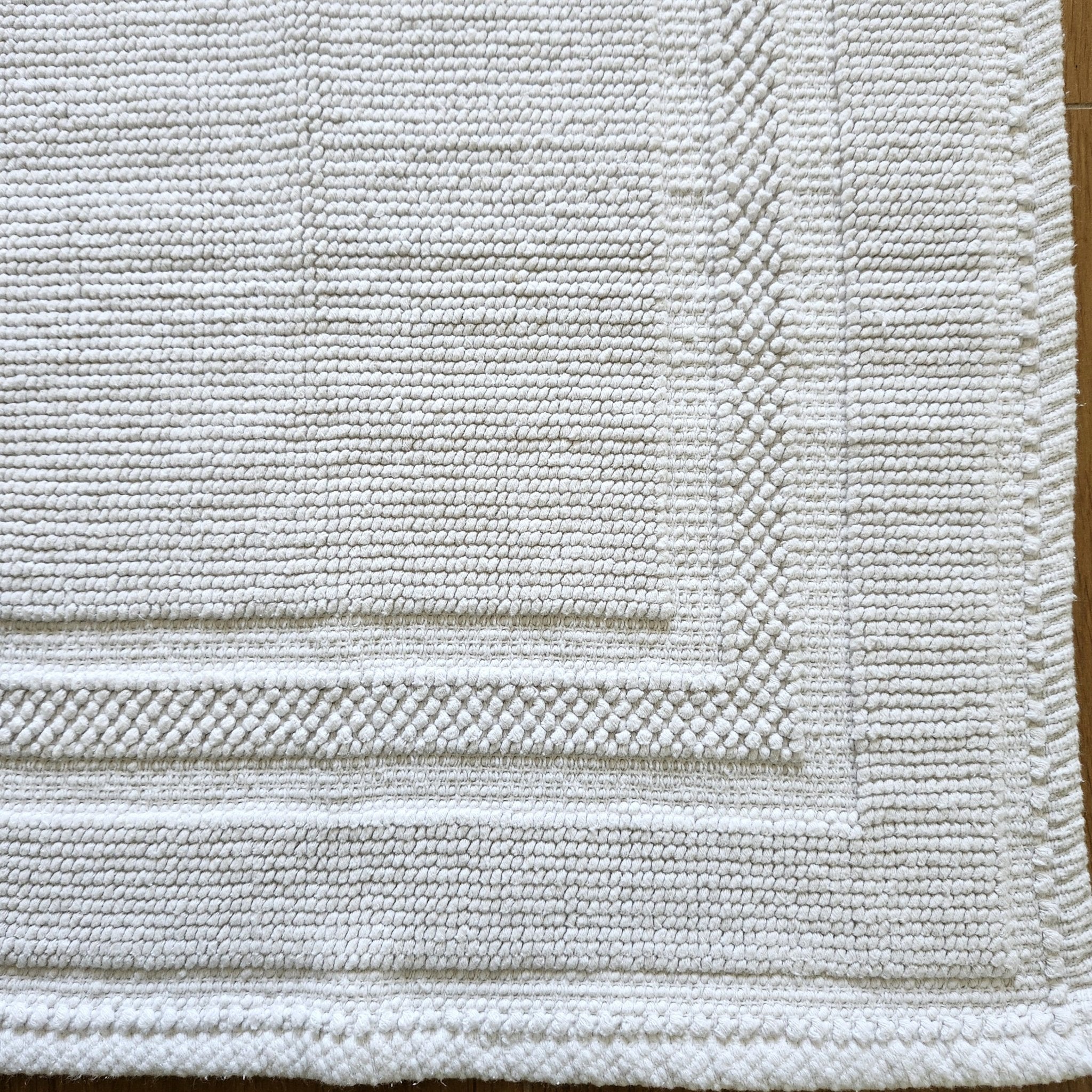 White stonewashed cotton bath mat with looped weave, soft and absorbent, 43 x 60 cm, made in India
