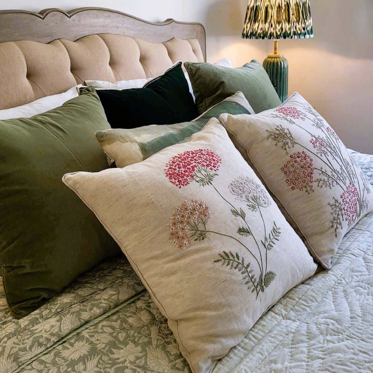 The cherry blossom cushion shown with the Spring Blossom cushion, both hand embroidered on linen