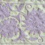 Detail of the hand embroidered lavender Suzani pattern on this pale green cotton throw from India.