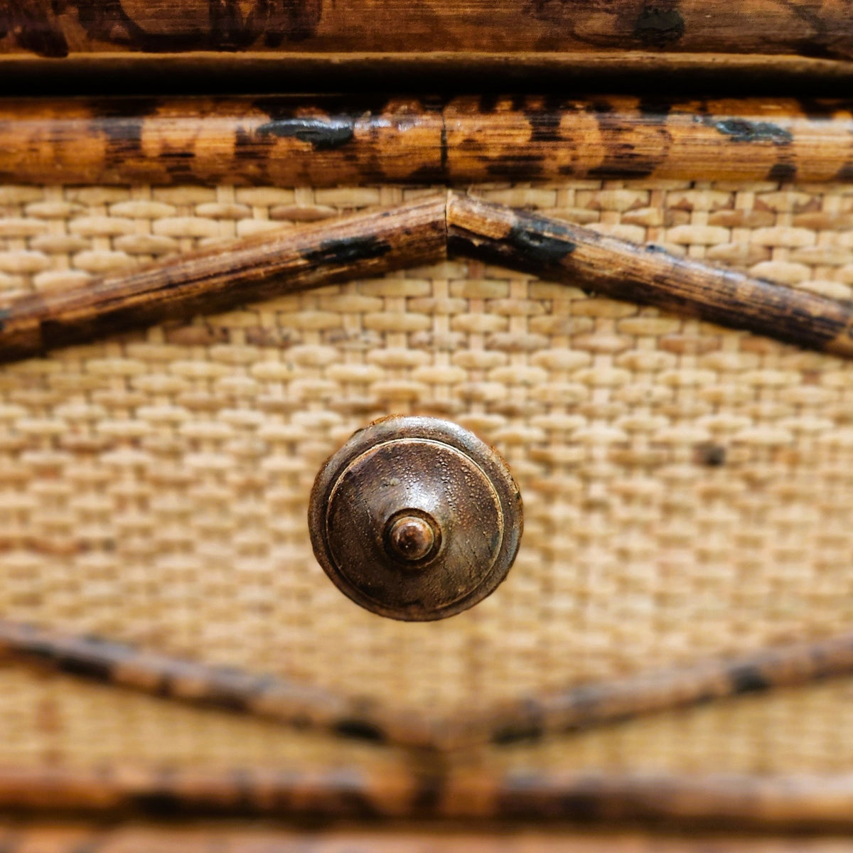 The cane chest seen from another angle, its three drawers each fitted with a finely carved wooden handle