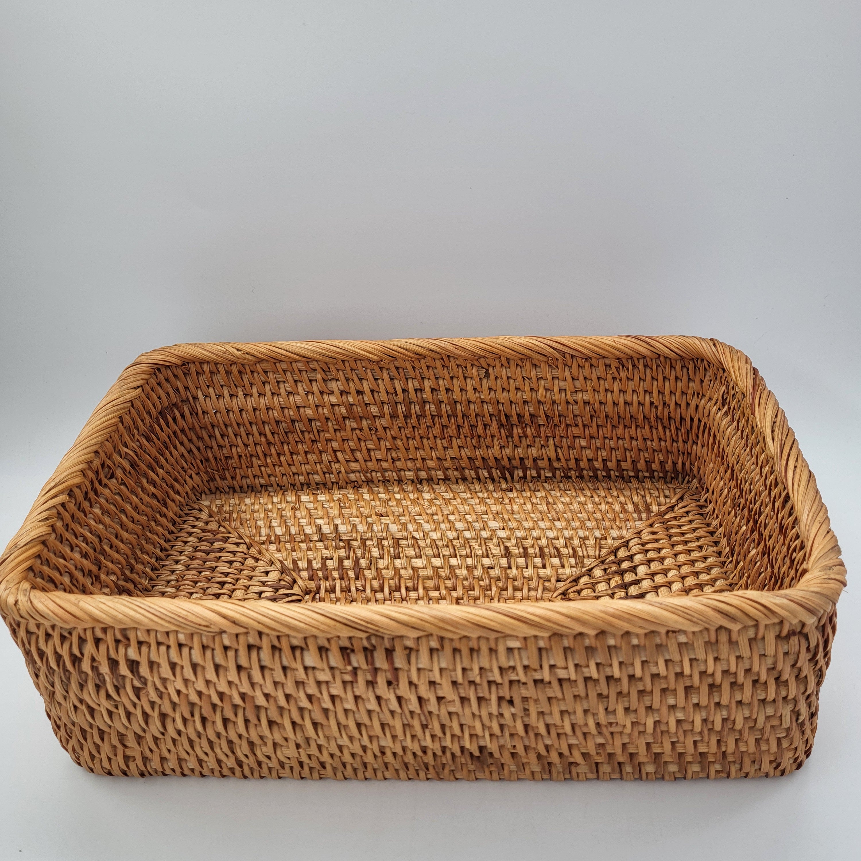 Rectangular handwoven natural rattan basket for home storage of throws, toys and household items, close-up view