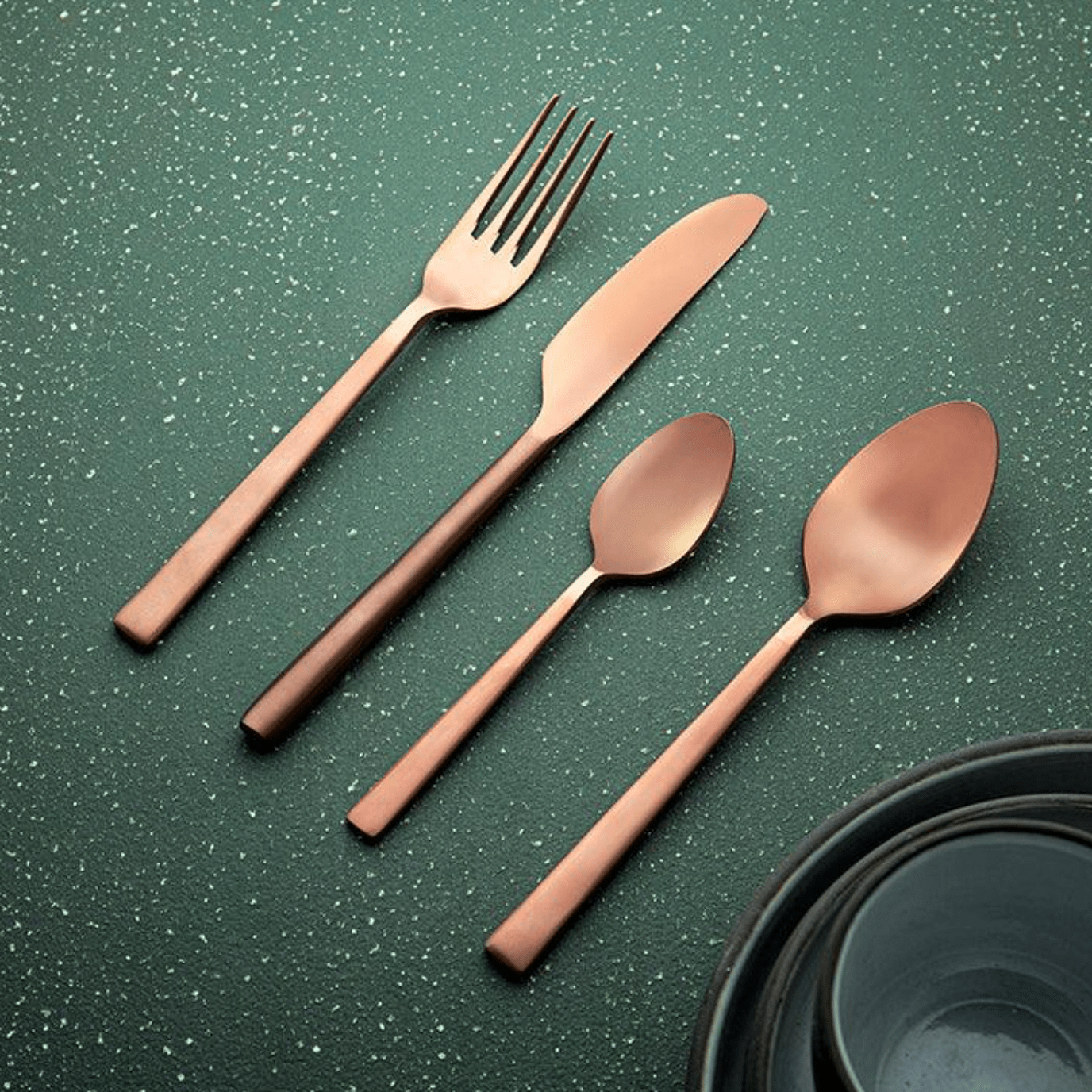 Four-piece stainless steel cutlery set with a rose gold satin finish, spoon, fork, knife and teaspoon