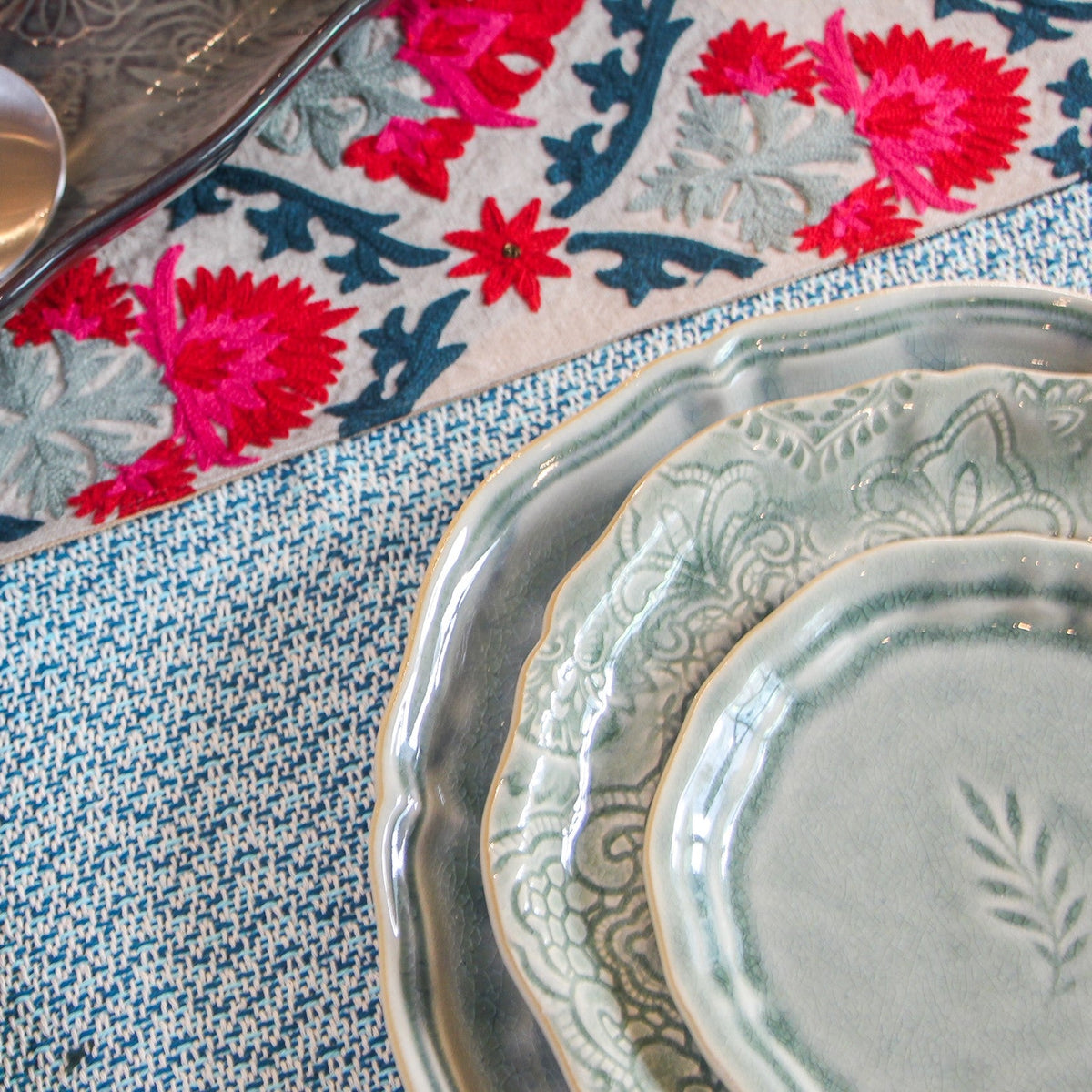Close view of the red, pink, blue and grey suzani embroidery worked by hand onto natural linen by artisans