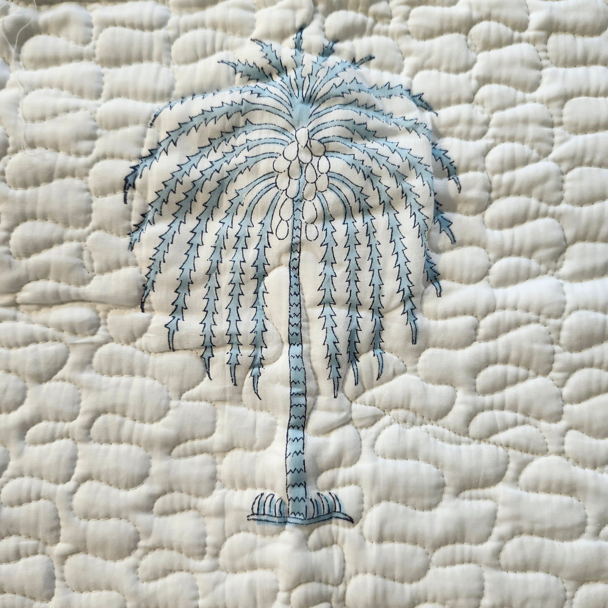 Reverse of the Cheetah bedspread, a blue geometric block print on white cotton, lightly quilted and made in India.