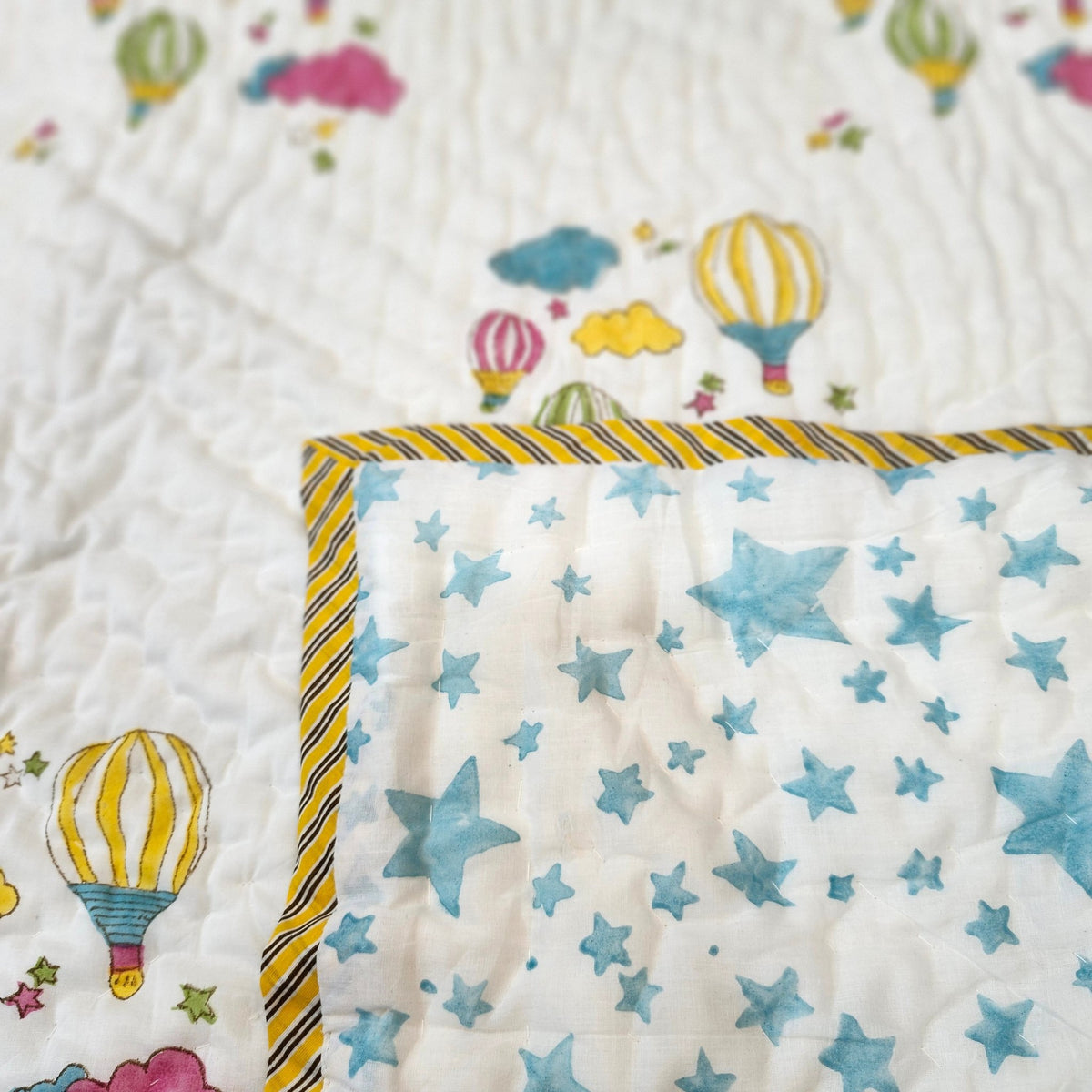 Child's organic cotton cambric quilt, balloon pattern on one side and blue stars on white on the other, usable either way