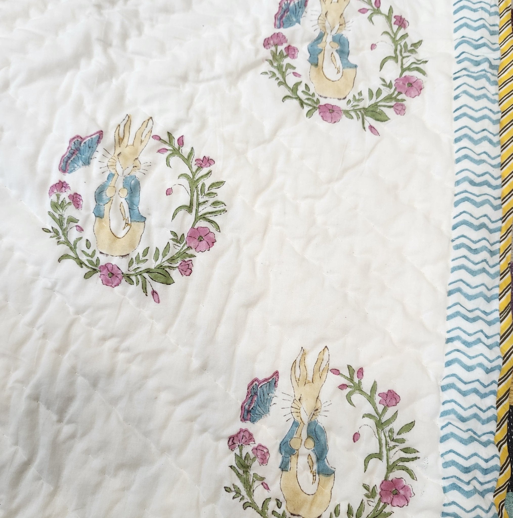 Soft organic cotton cambric quilt for a child, printed with Peter Rabbit on one side and blue spots on the other