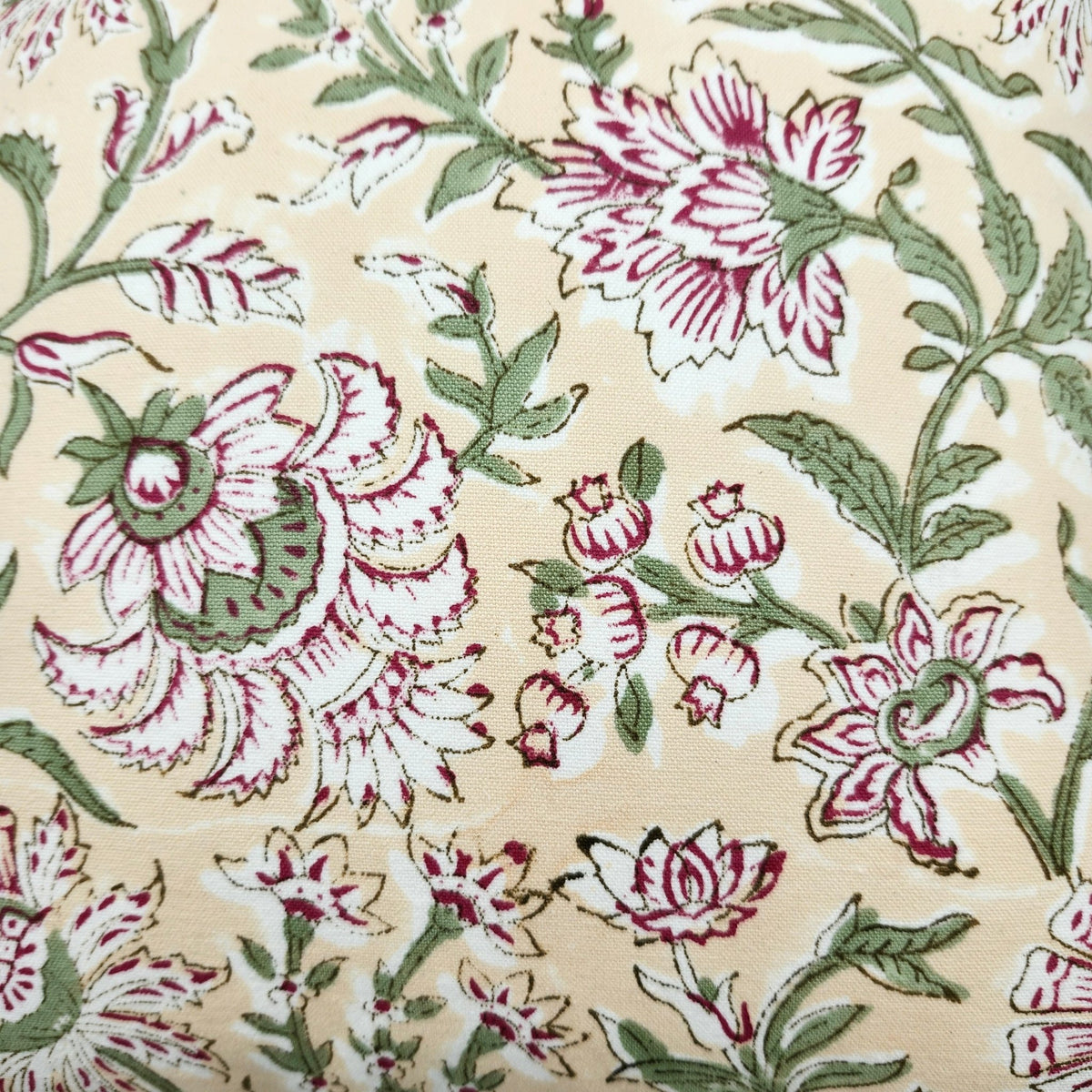 Cushion cover with hand block printed pink flowers and green leaves, suited to white bed linens or a small sofa