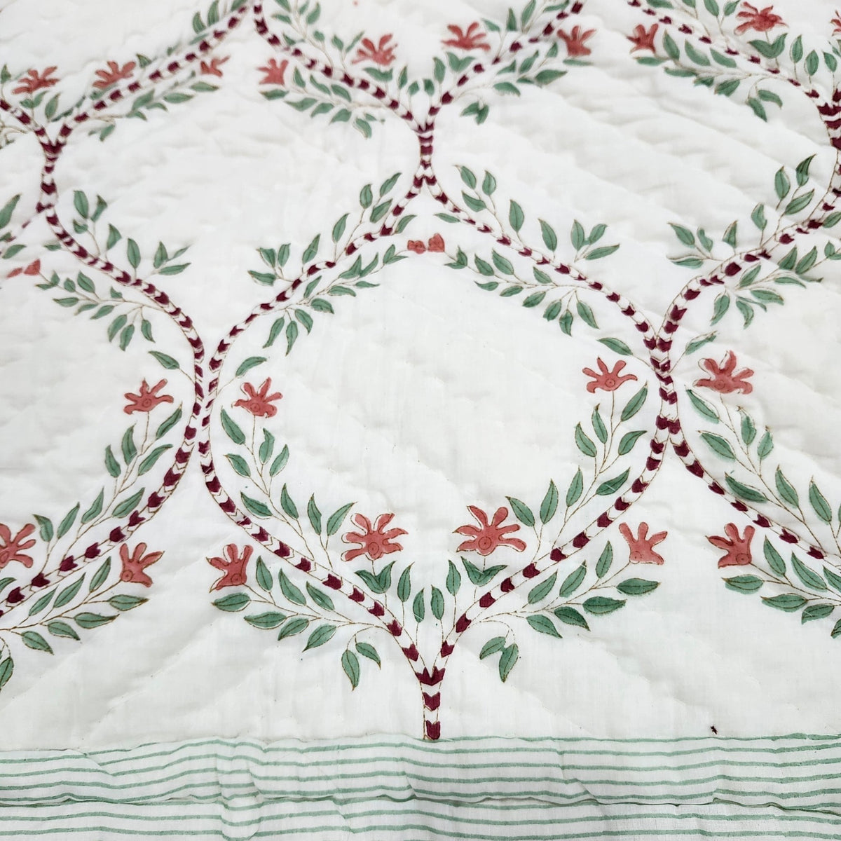 Single size quilt in a green and white trellis block print, each piece slightly different as it is printed by hand