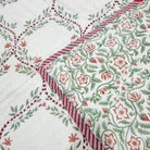 Green trellis block print quilt in a single bed size, with the floral reverse side in the same colours