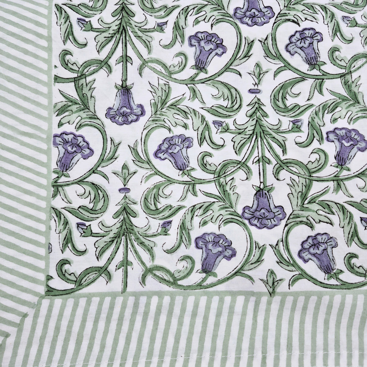 Cotton block print tablecloth with violet flowers and green foliage on white, 150 x 225cm, with a striped border.